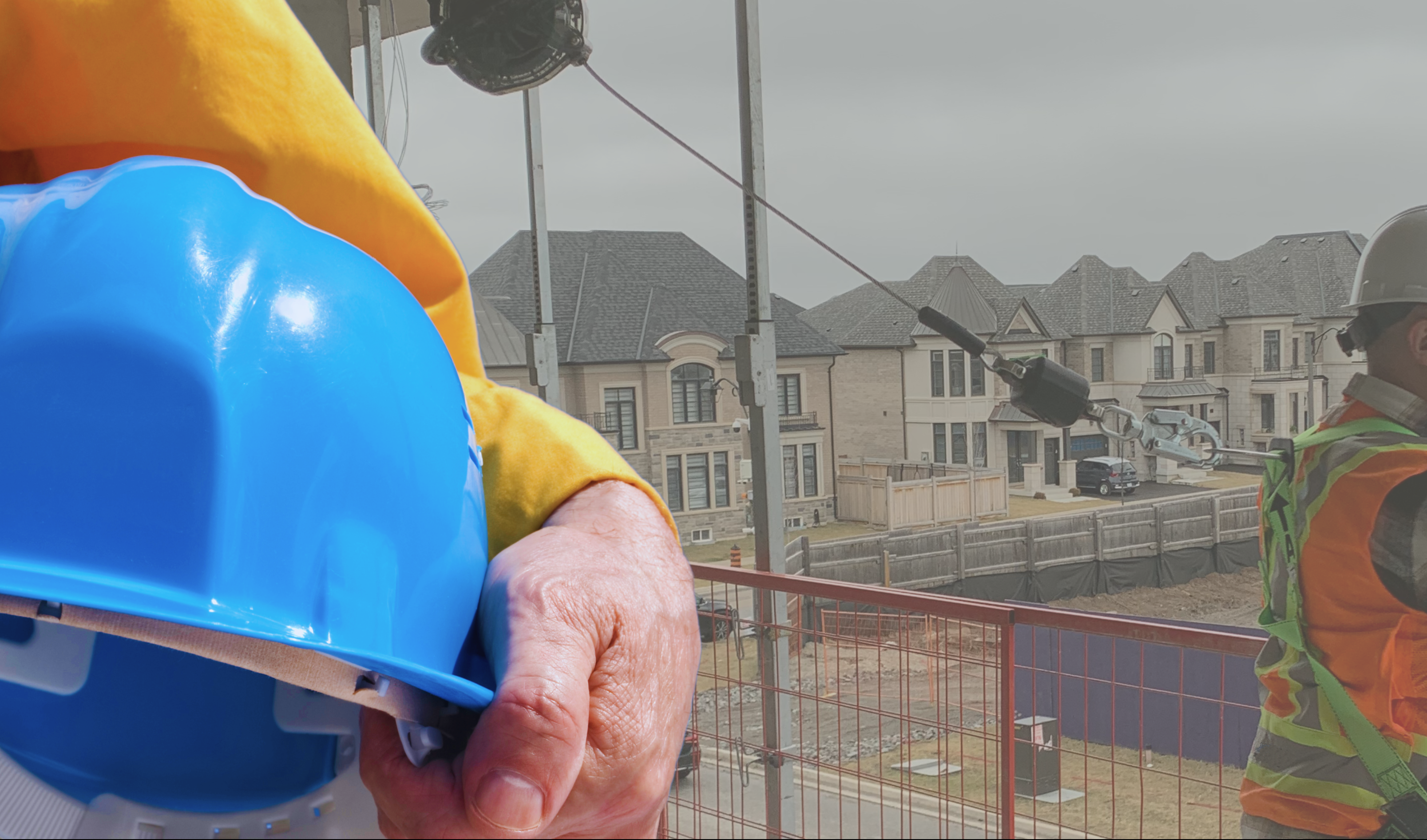 Person holding a blue hardhat with worker in background wearing a full body harness while tied off to an acnhor point using a self-retracting lifeline. 2024 construction health and safety compliance plans